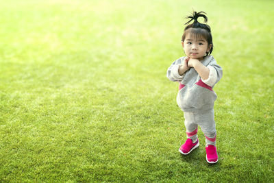 Portrait of cute baby girl standing on grassy field