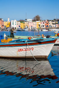 Fishing boats moored at harbor against buildings in city