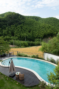 Swimming pool by lake against sky