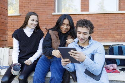 Man sharing tablet pc with friends on university campus