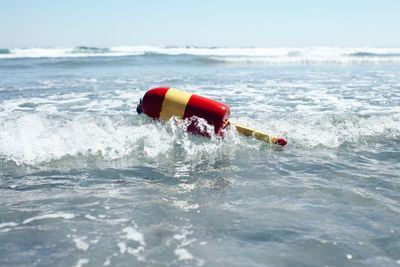 Red buoy floating on water in sea against sky