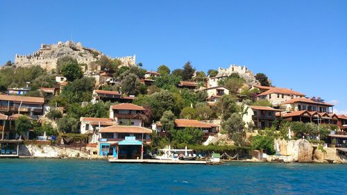 Town by calm blue sea against clear sky