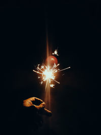 Cropped hand holding sparkler at night