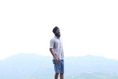 Young man wearing turban looking away against clear sky