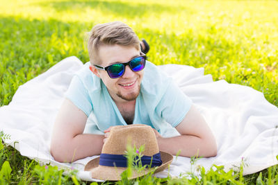 Young man wearing sunglasses lying down on field
