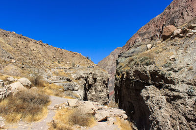 Low angle view of rock formation against clear blue sky