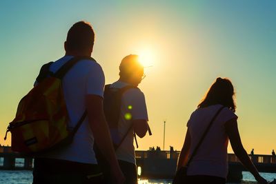 Rear view of people standing against sky during sunset