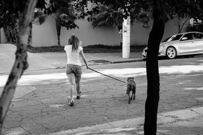 Rear view of woman with dog walking on street