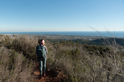 Woman contemplates the landscapes of the garraf natural park while walking the paths of a mountain.