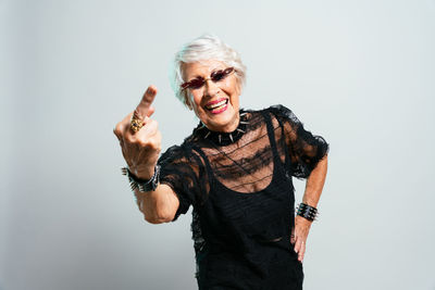 Portrait of young woman with arms raised standing against white background