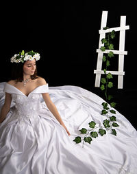 Woman sitting on white wall