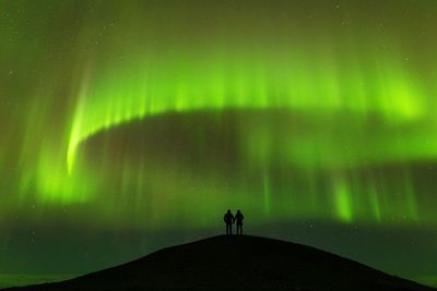 Silhouette people standing on land against sky at night