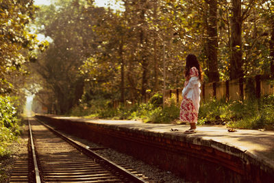 Rear view of woman walking on railroad track