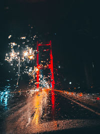 Illuminated road in city during rainy season at night