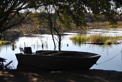 Boat moored by lake against trees