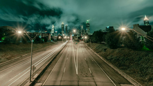 Illuminated city street against sky at night