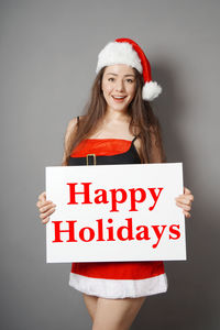 Portrait of young woman standing against gray background