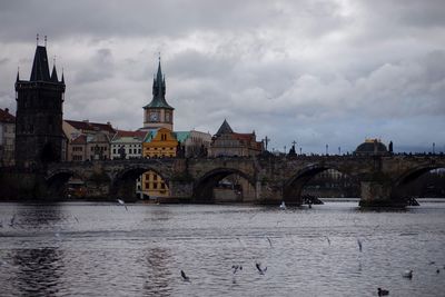 Arch bridge over river against buildings in city