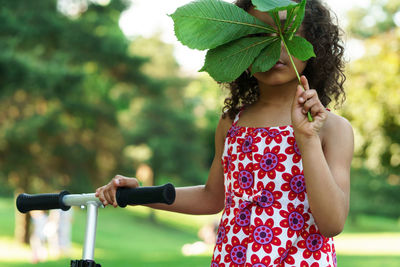Girl holding leaf while standing at park