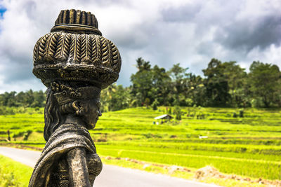 Close-up of statue on field against sky - bali  indonesia