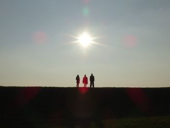 Silhouette people on field against sky during sunset