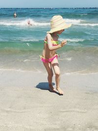 Bikini girl running away from waves at beach during sunny day