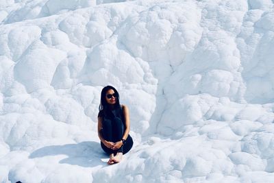 Full length of woman sitting on snow