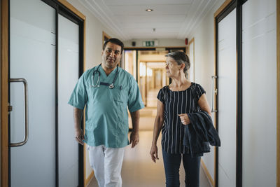 Doctor discussing with senior patient while walking in corridor of hospital