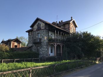 Old building by road against clear blue sky