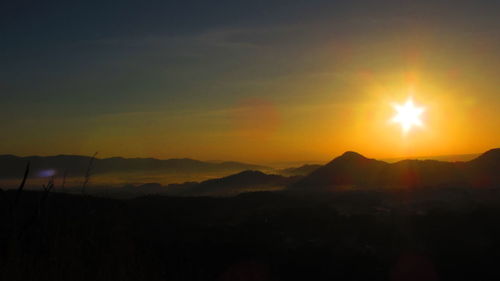 Sun shining through clouds over mountains