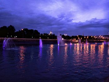 River by illuminated city against sky at night