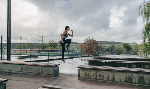 Woman standing on railing against sky in city