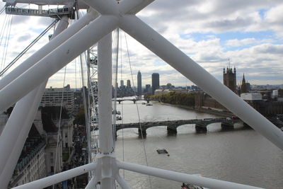 Bridge over river in city against cloudy sky