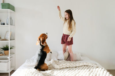 Girl playing with dog on bed at home