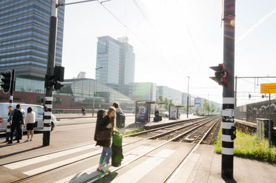 People waiting at railroad station in city against sky