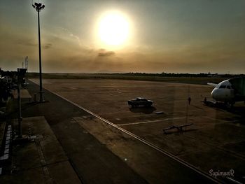 Airplane on runway against sky during sunset