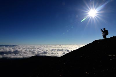 Silhouette woman on mountain against blue sky