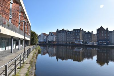 Reflection of buildings on river against sky