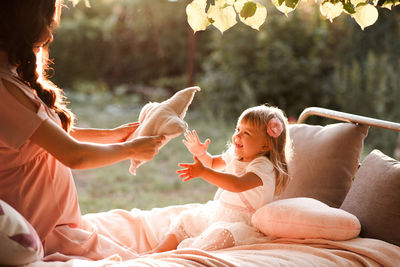 Side view of woman sitting on bed with daughter