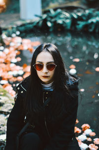 Portrait of beautiful woman in sunglasses against pond