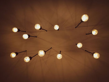 Low angle view of illuminated pendant lights hanging from ceiling