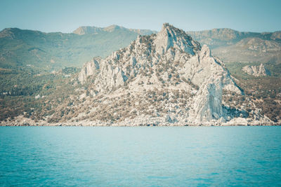 Scenic view of sea and mountains against blue sky