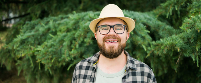 Portrait of young man wearing sunglasses while standing against plants