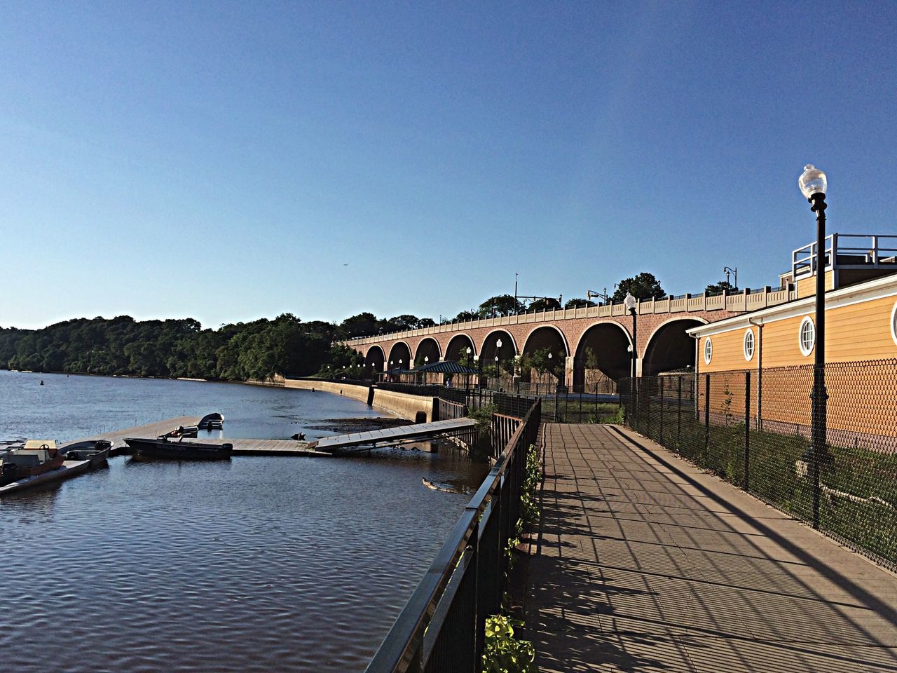 clear sky, copy space, water, built structure, architecture, transportation, connection, bridge - man made structure, blue, railing, the way forward, river, bridge, engineering, sea, pier, nautical vessel, building exterior, long, tranquility