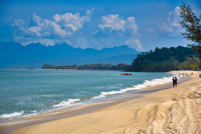 Waves of the azure andaman sea under the blue sky reaching the shores of cenang beach in langkawi