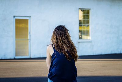 Rear view of woman sitting against building