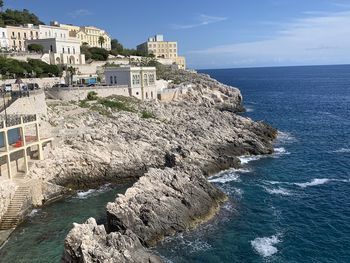 Scenic view of sea by buildings against sky