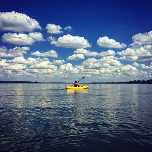 Man rowing boat in sea against sky