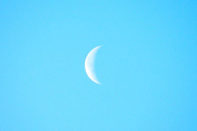 Low angle view of half moon against clear blue sky