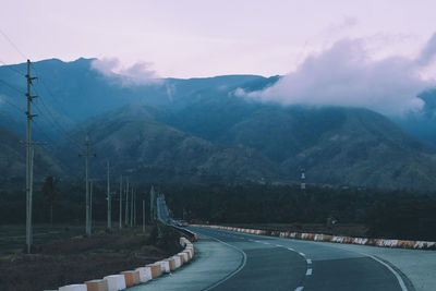 Road leading towards mountains against sky